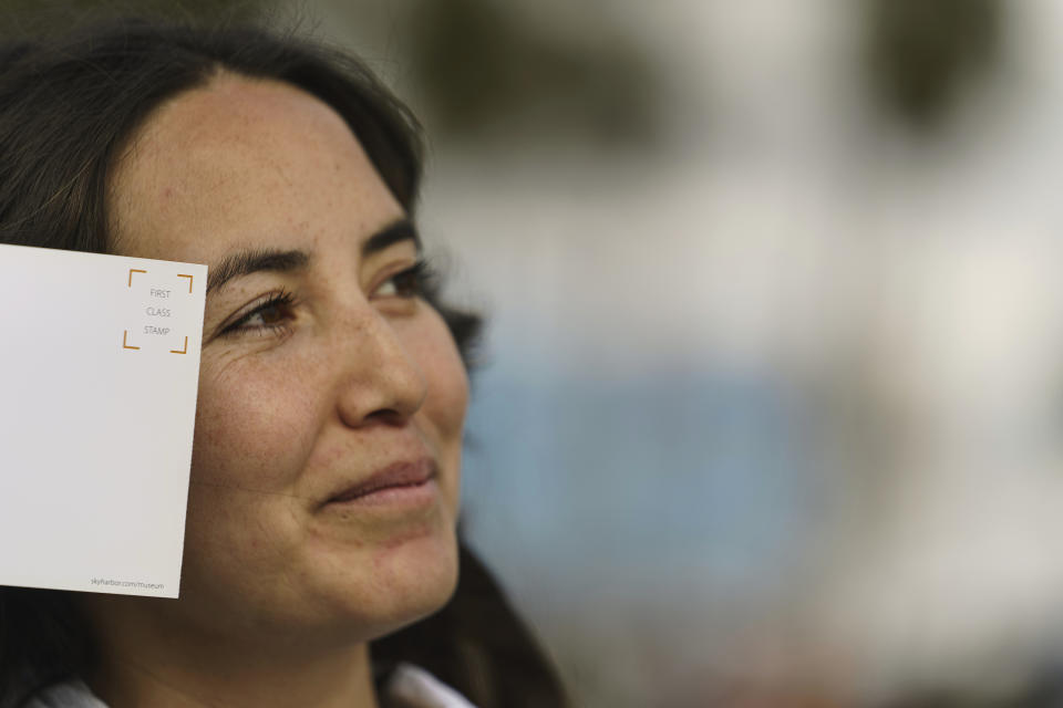 Expert skateboarder Di'Orr Greenwood, an artist born and raised in the Navajo Nation in Arizona and whose work is featured on the new U.S. stamps, holds an art gallery postcard waiting for her own skateboard stamp in the Venice Beach neighborhood in Los Angeles Monday, March 20, 2023. On Friday, March 24, the U.S. Postal Service is debuting the "Art of the Skateboard," four stamps that will be the first to pay tribute to skateboarding. The stamps underscore how prevalent skateboarding has become, especially in Indian Country, where the demand for designated skate spots has only grown in recent years. (AP Photo/Damian Dovarganes)