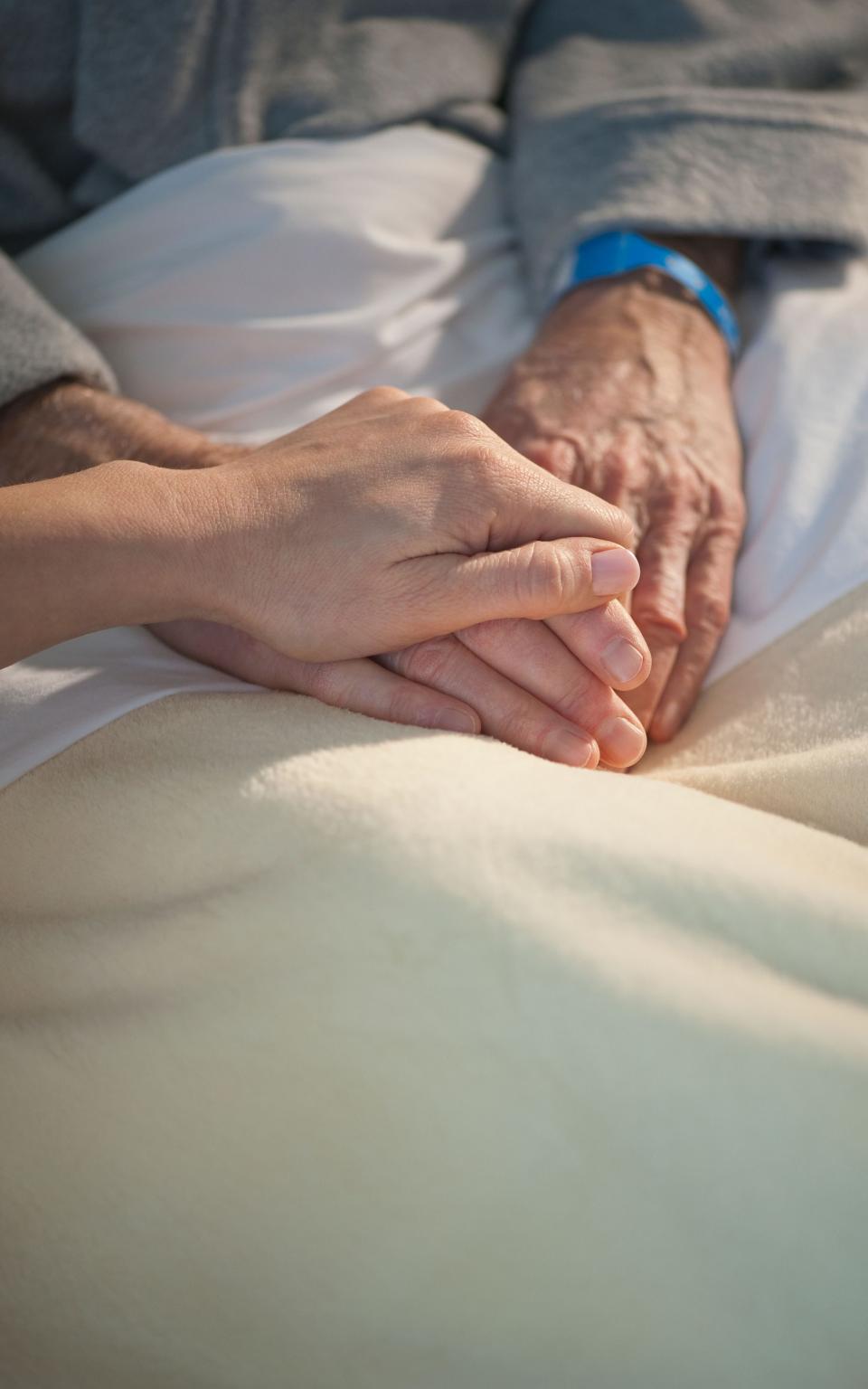 Nurse holding elderly man's hand - Credit:  Tetra Images / Alamy