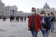 FILE - In this Thursday, Feb. 27, 2020 file photo, a couple wearing face masks stroll outside St. Peter's Square, at the Vatican. A U.S. government advisory urging Americans to reconsider travel to Italy is the ‘’final blow'' to the nation's tourism industry due to a new virus, the head of Italy's hotel federation said Saturday, Feb. 29, 2020. (AP Photo/Gregorio Borgia, file)