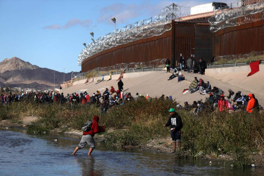 TOPSHOT – Migrants walk across the Rio Grande to surrender to US Border Patrol agents in El Paso, Texas, as seen from Ciudad Juarez, Chihuahua state, Mexico, on December 13, 2022. (Photo by Herika Martinez / AFP) (Photo by HERIKA MARTINEZ/AFP via Getty Images)