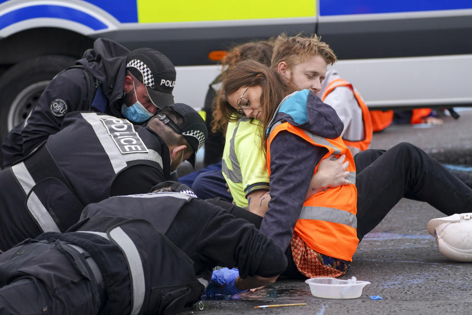 <p>Police officers work to free protesters who had glued themselves to a slip road at Junction 4 of the A1(M), near Hatfield, where climate activists carried out a further action after demonstrations which took place last week across junctions in Kent, Essex, Hertfordshire and Surrey. Picture date: Monday September 20, 2021.</p>
