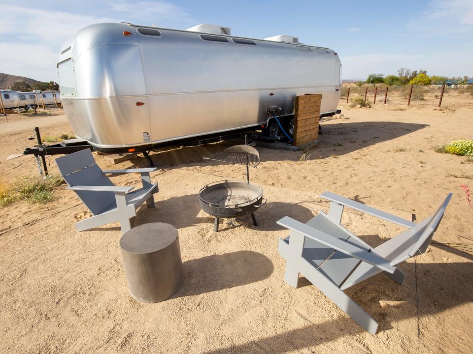 Airstream trailers with a fire pit, seating outside at Autocamp's Joshua Tree location.
