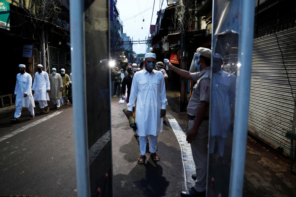 A policeman checks the temperature of Muslims arriving to offer Eid al-Adha prayers at the Jama Masjid (Grand Mosque) during the outbreak of the coronavirus disease (COVID-19), in the old quarters of Delhi, India, August 1, 2020. REUTERS/Adnan Abidi