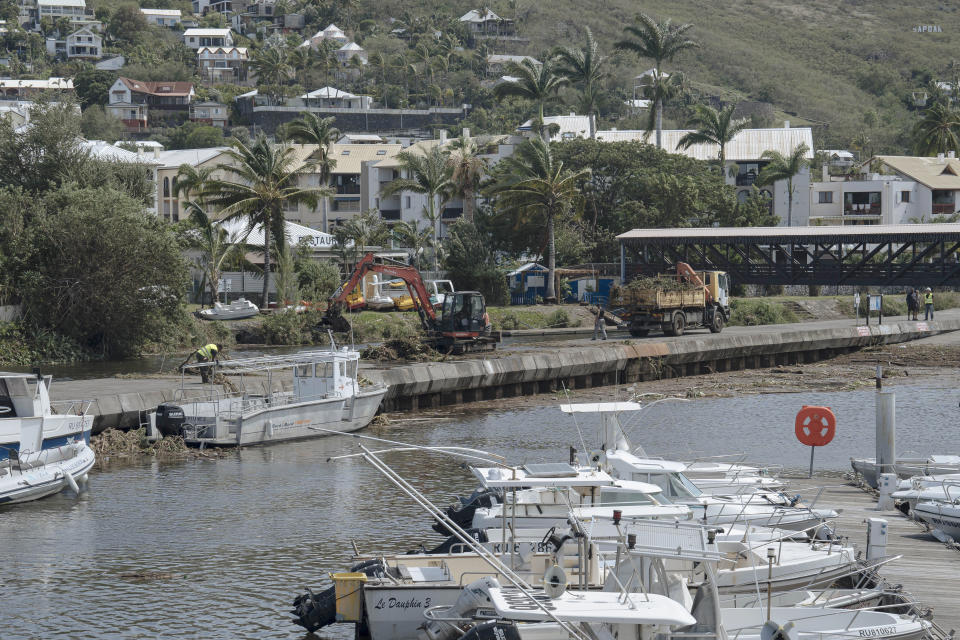 Workers clean up trees and debris on the marina of Saint-Gilles les Bains on the French Indian Ocean island of Reunion, Tuesday, Jan. 16, 2024. Tropical cyclone Belal had battered the French island of Reunion, where the intense rains and powerful winds left about a quarter of households without electricity after hitting Monday morning, according to the prefecture of Reunion. (AP Photo/Lewis Joly)