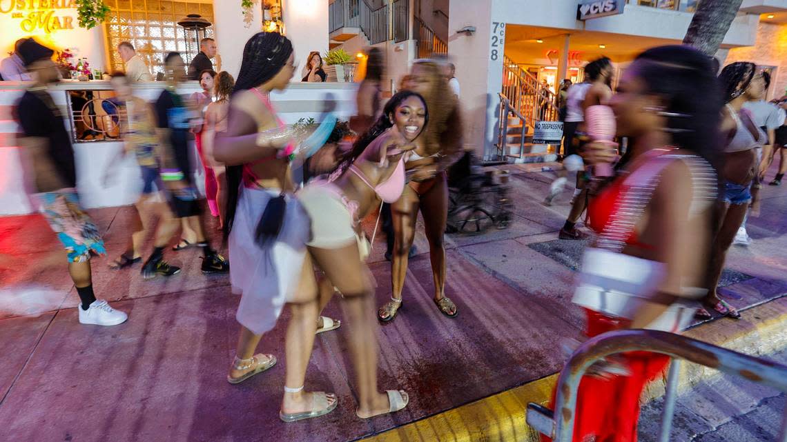 Women dance on the sidewalk along Ocean Drive during spring break on Miami Beach, Florida on Sunday, March 17, 2024.