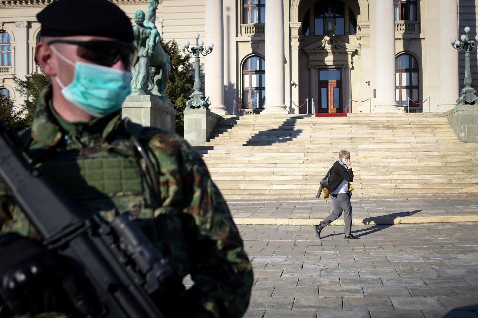 A Serbian Army soldier wearing gloves and a face masks as preventive measures against COVID-19 (novel Coronavirus) stands guard in front of the National Assembly in Belgrade on March 16, 2020. - Serbia declared a state of emergency on March 15, 2020 to halt the spread of the new coronavirus, shutting down many public spaces, deploying soldiers to guard hospitals and closing the borders to foreigners. Serbia's President Aleksandar Vucic said the new restrictions were necessary to "save our elderly" in the Balkan state of some seven million, which has detected around 55 infections of COVID-19 so far with limited testing. (Photo by Oliver BUNIC / AFP) (Photo by OLIVER BUNIC/AFP via Getty Images)