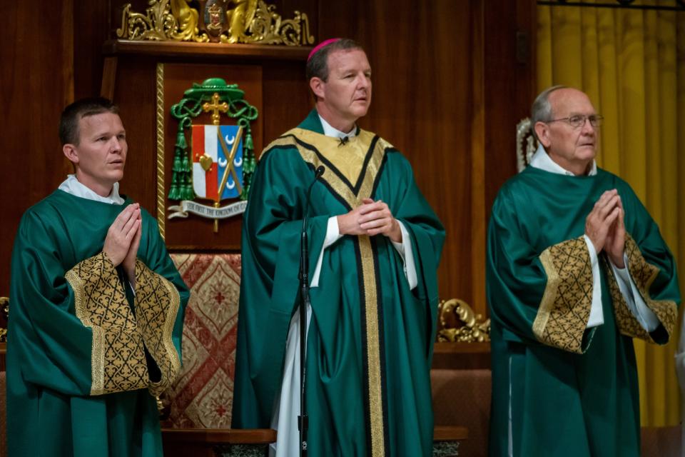 A portrait of the Pohlmeier family on the altar includes the newly-installed Bishop Erik Pohlmeier, center, his brother, Deacon Jason Pohlmeier, left, and his father, Deacon Tom Pohlmeier. On July 24, 2022, Rev. Erik Pohlmeier, the 11th Bishop of the Diocese of St. Augustine, was welcomed into his new church home, the Cathedral Basilica of St. Augustine, to celebrate his first Mass there. A reception at The Treasury on the Plaza followed the service.