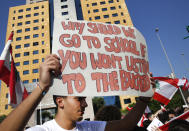 A student protester holds a placard as he protests against the government in front of the education ministry in Beirut, Lebanon, Friday, Nov. 8, 2019. Lebanese protesters are rallying outside state institutions and ministries to keep up the pressure on officials to form a new government to deal with the country's economic crisis. (AP Photo/Hussein Malla)