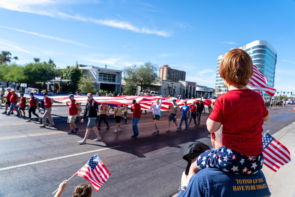 Michelle Deaver, 3, sits on the shoulders of her father, Jesse Deaver, 30, as they watch a Veterans Day parade in Phoenix on Nov. 11, 2022.