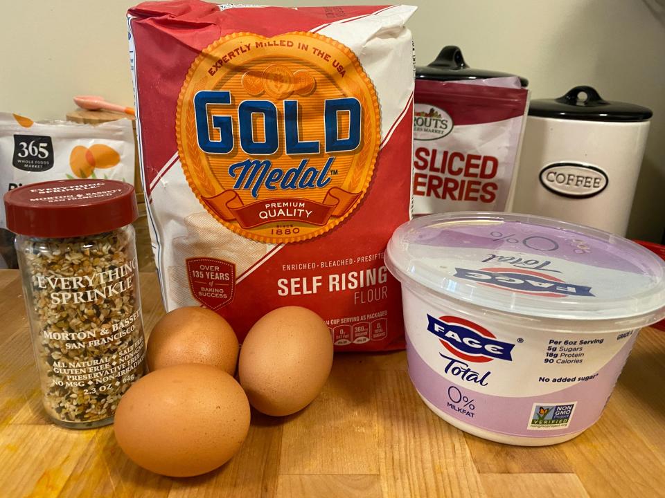 A photo of everything seasoning, self-rising flour, yogurt, and eggs on wood.