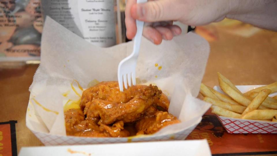 JENNA EASON/THE TELEGRAPH Macon, GA, 06/18/2019: Reporter Justin Baxley sticks his fork into a chicken strip covered in Mercer Gold sauce at Francar’s Buffalo Wings for #FoodieFriday.