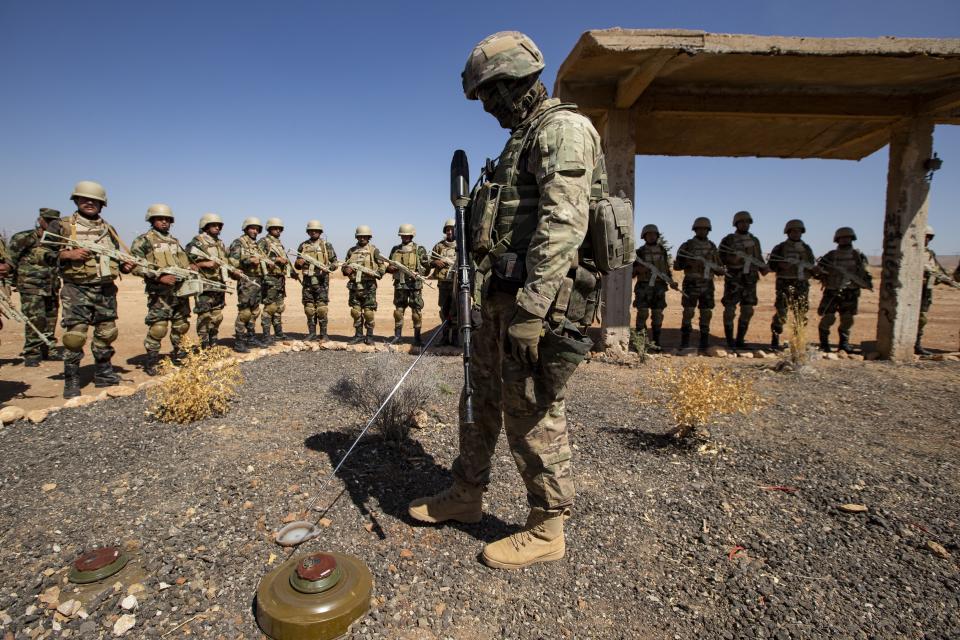 A masked Russian military center, foreground, explains different kinds of mines to Syrian soldiers during military training exercises at a base about 50-kilometers away from Damascus, Syria, Tuesday, Sept. 24, 2019. (AP Photo/Alexander Zemlianichenko)