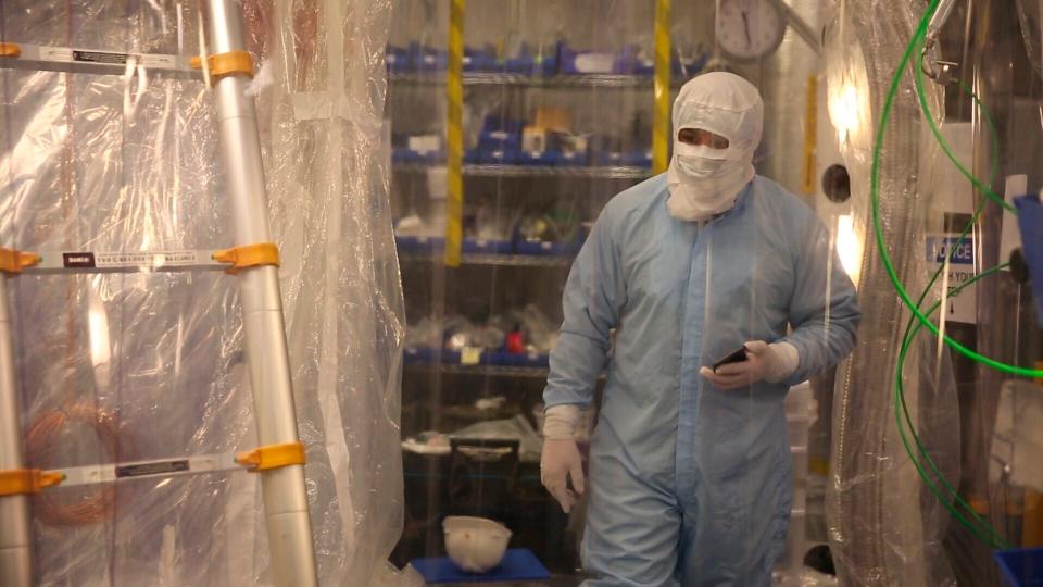 A lab worker wearing a bodysuit to avoid contaminating the dark matter detector works in the Sanford Underground Research Facility in Lead, S.D., on Dec. 8, 2019.  Scientists have begun a new search for mysterious dark matter in a former gold mine a mile underground. Dark matter makes up the vast majority of the mass of the universe but scientists don't know what it is. (AP Photo/Stephen Groves)