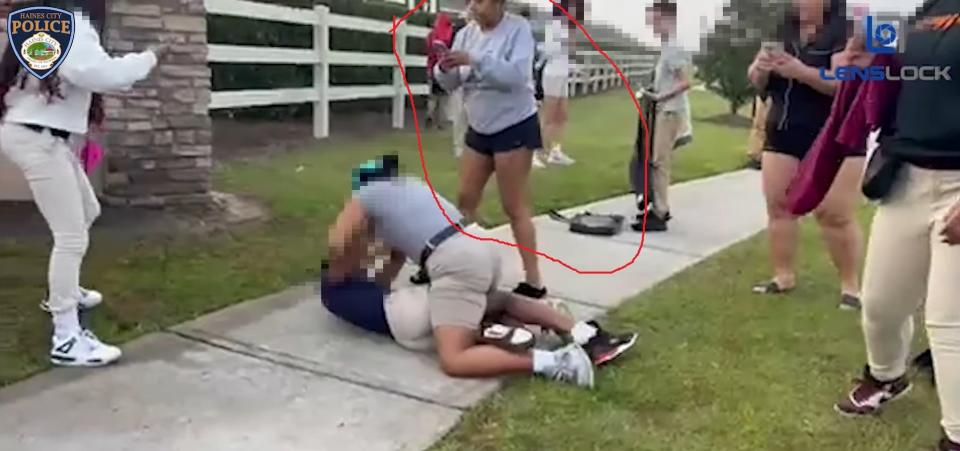 Taitayana Duffy (circled) appears to be recording the fight and allegedly cheering the student