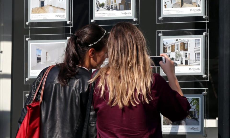 Young women look at an estate agent window