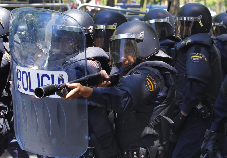 A riot policeman shoot rubber bullets towards demonstrators after demonstrators threw bananas during a coal miners march to the Minister of Industry building in Madrid, Wednesday, July 11, 2012. Coal miners angered by huge cuts in subsidies converged on Madrid Tuesday for protest rallies after walking nearly three weeks under a blazing sun from the pits where they eke out a living. (AP Photo/Andres Kudacki)