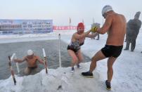 Winter swimmers get out of the icy waters of the partially frozen Songhua River in Harbin, Heilongjiang province December 28, 2013. Temperatures in Harbin on Saturday reached as low as minus 21 degrees Celsius (minus 5.8 degrees Fahrenheit). REUTERS/Sheng Li (CHINA - Tags: SOCIETY SPORT SWIMMING ENVIRONMENT) CHINA OUT. NO COMMERCIAL OR EDITORIAL SALES IN CHINA