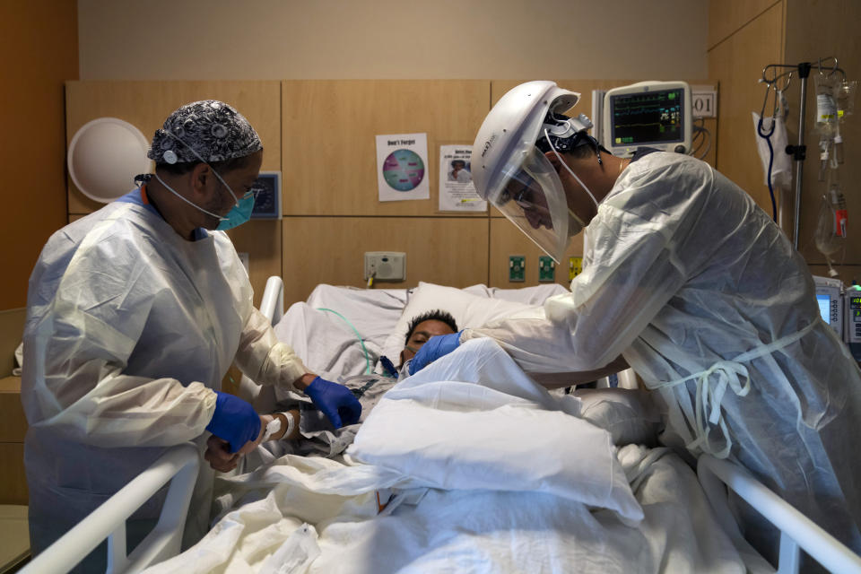 FILE - In this Nov. 19, 2020 file photo, Dr. Rafik Abdou, right, and respiratory therapist Babu Paramban check on a COVID-19 patient at Providence Holy Cross Medical Center in the Mission Hills section of Los Angeles. California reported more than 50,000 new coronavirus cases and 293 deaths on Wednesday, Dec. 16, 2020, setting new daily records as hospitals struggled to keep up with the surge. Southern California and the state's Central Valley — regions that together include 23 counties and most of the state's nearly 40 million residents — had exhausted their regular supply of intensive care beds and many hospitals were tapping into their "surge" capacity. (AP Photo/Jae Hong, File)