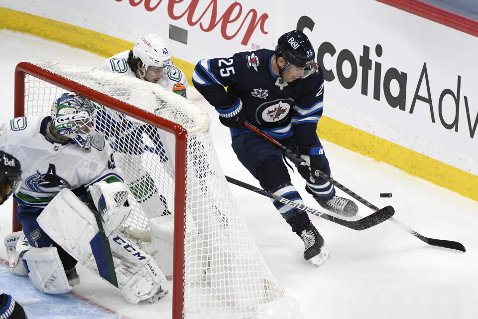 Winnipeg Jets' Paul Stastny (25) carries the puck around Vancouver Canucks' Quinn Hughes (43) during the second period of an NHL hockey game Tuesday, May 11, 2021, in Winnipeg, Manitoba. (Fred Greenslade/The Canadian Press via AP)