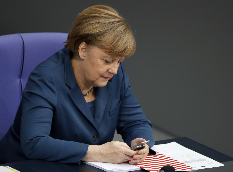 FILE - In this Thursday, Nov. 28, 2013 file photo German Chancellor Angela Merkel holds a mobile phone during a meeting of the German federal parliament, Bundestag, in Berlin, Germany. Cybersecurity researchers in Europe say they've discovered a flaw in an encryption algorithm used by cellphones that may have allowed attackers to eavesdrop on some data traffic for more than two decades. In a paper published Wednesday, researchers from Germany, France and Norway said the flaw affects the GPRS mobile data standard. (AP Photo/Michael Sohn, file)