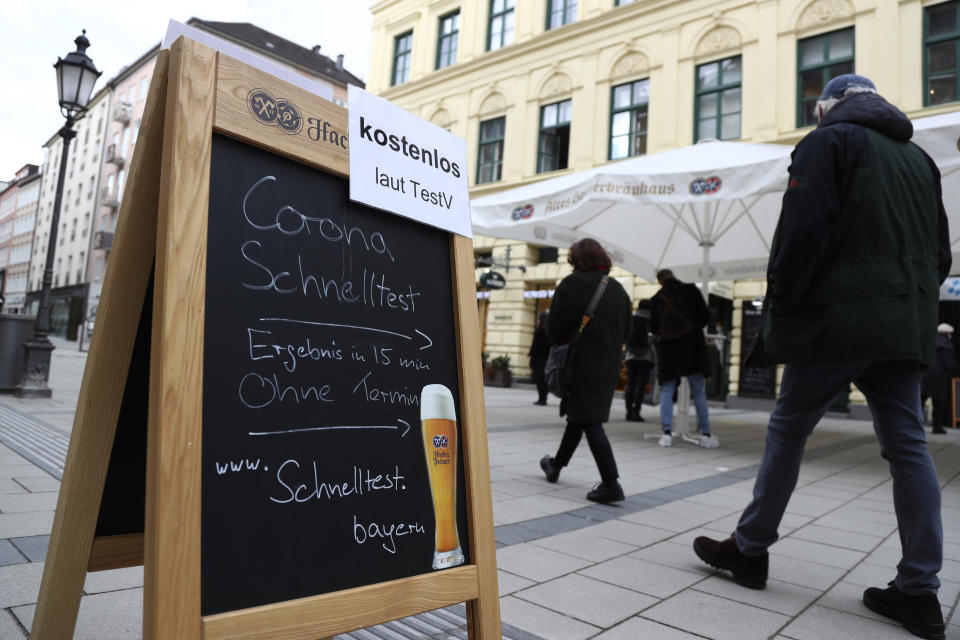 People pass the traditional Bavarian restaurant 'Hackerbraeuhaus' where a corona test center now works for SARS CoV-2 rapid tests downtown in Munich, Germany, Tuesday, March 23, 2021. (AP Photo/Matthias Schrader)