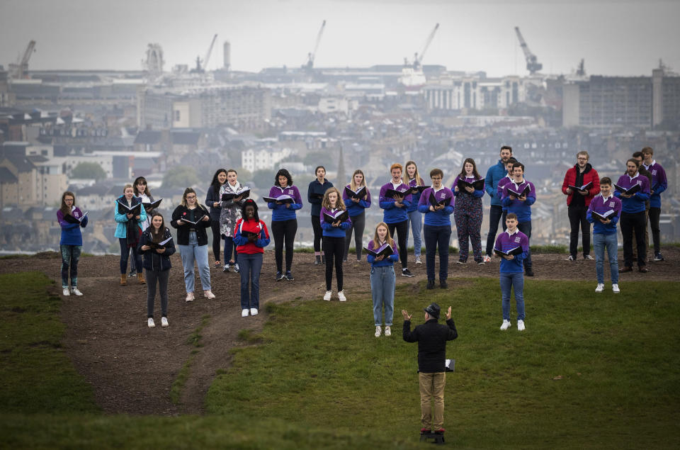 The National Youth Choir of Scotland, with founder and conductor Christopher Bell meet on Calton Hill, to sing, in Edinburgh, Monday May 17, 2021. Most of Scotland moves to Level 2 restrictions enabling up to 30 people to meet outside. The choir last met and performed together in March 2020 which is when the choir last met and performed together. (Jane Barlow/PA via AP)