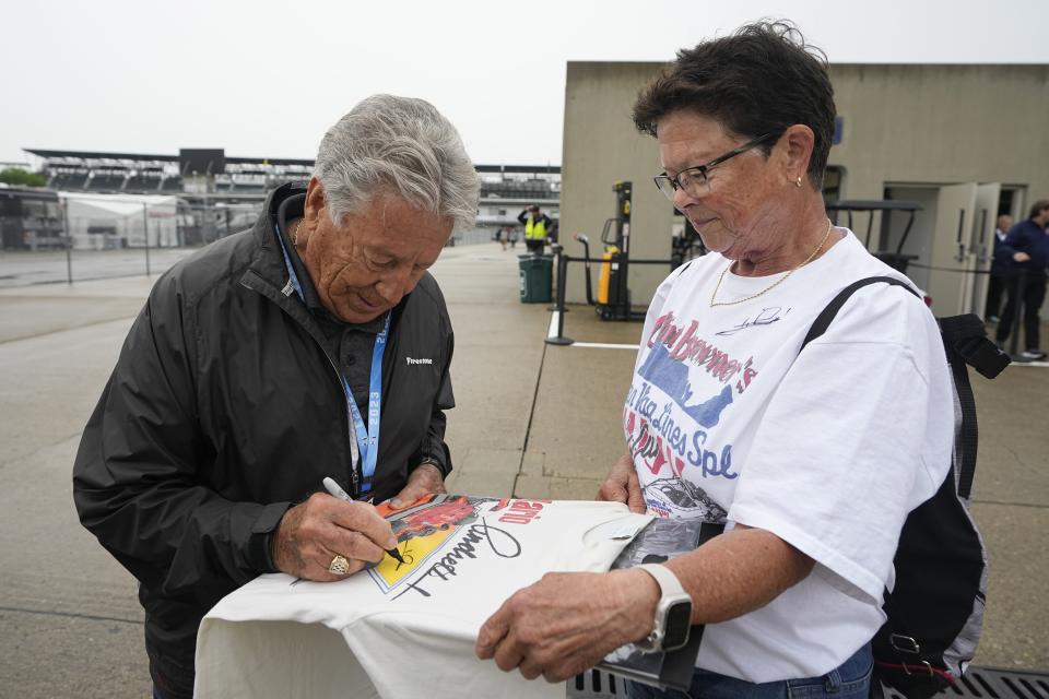 Mario Andretti signs an autograph for a fan during a rain delay before practice for the Indianapolis 500 auto race at Indianapolis Motor Speedway, Tuesday, May 16, 2023, in Indianapolis. (AP Photo/Darron Cummings)