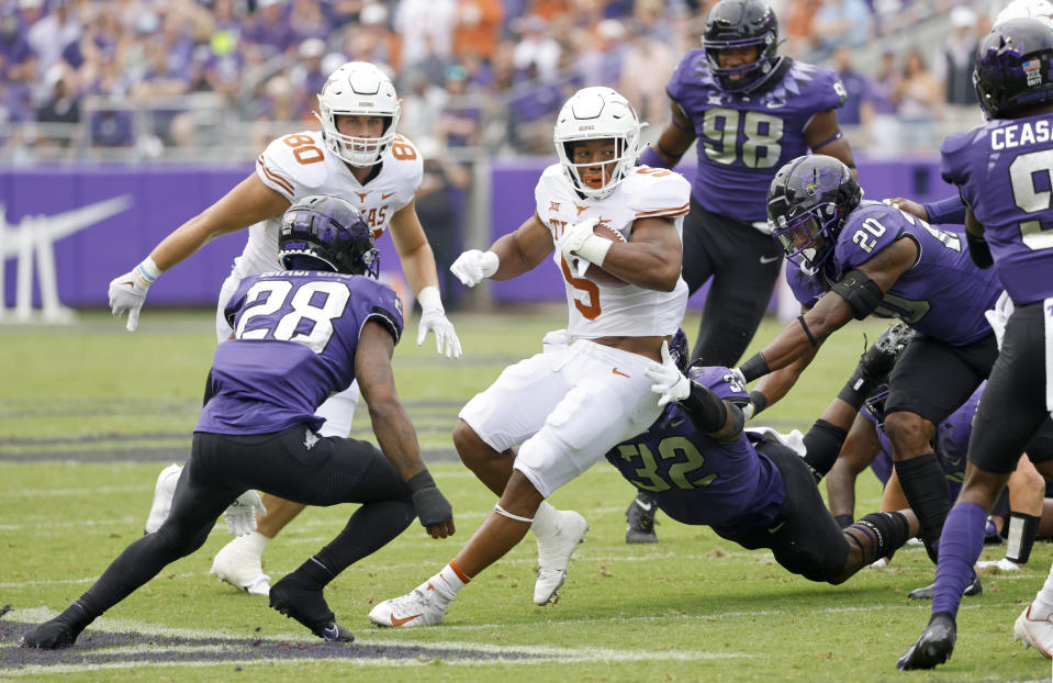 Texas running back Bijan Robinson (5) carries the the ball as a host of TCU defenders close in during the first half of an NCAA college football game Saturday, Oct. 2, 2021, in Fort Worth, Texas. (AP Photo/Ron Jenkins)