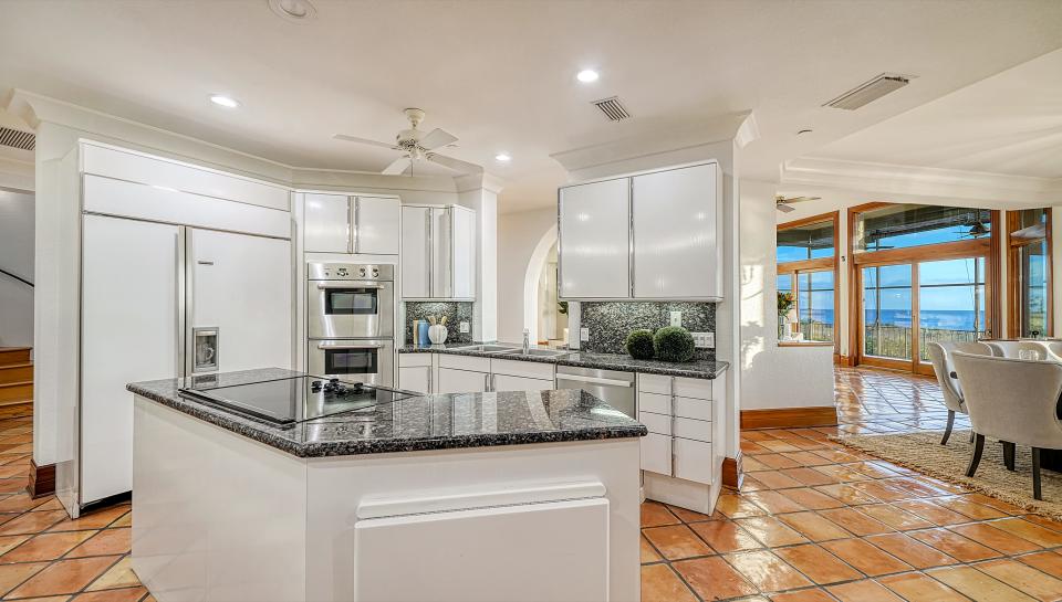 The kitchen is white, contemporary in styling with dark granite counters and sand-colored glazed tile.