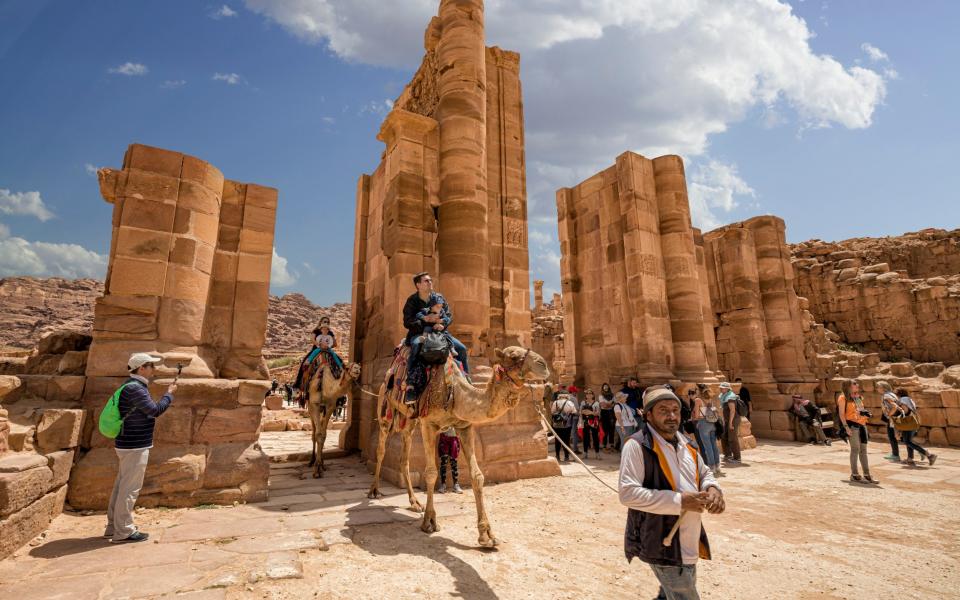 A tour guide leads a camel through the door of the Tremenos, Jordan