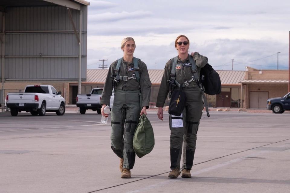 two women in flight suits walk around an air force base