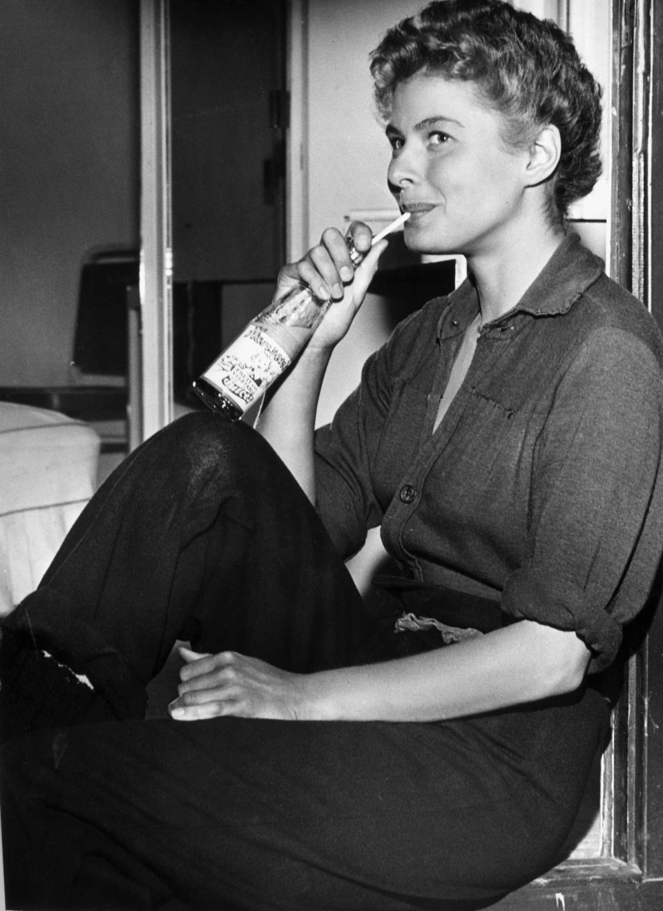 The actress sitting on a window ledge, sipping juice from a glass bottle with a straw, on the set of director Sam Wood's film, "For Whom the Bell Tolls."&nbsp;