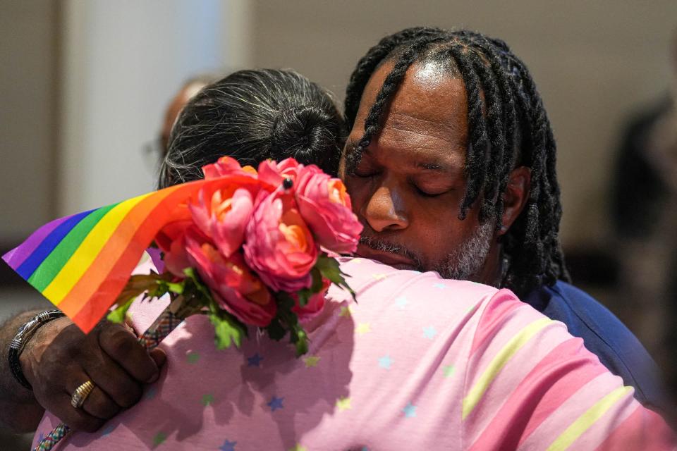Anthony Hill is hugged after being presented flowers with a pride flag attached to them at the Cedar Park City Council meeting Thursday. Hill's daughter, Akira Ross, was killed last week in Cedar Park by a stranger gas station who yelled gay slurs at her, according to an arrest affidavit.