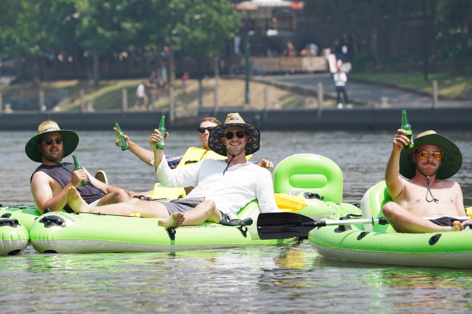 A team of landscapers enjoy their work Christmas party floating down the Yarra River during hot weather in Melbourne.