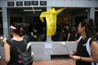 People pay respects at the site where a man fell from a scaffolding at the Pacific Place complex while protesting against a proposed extradition bill, near a raincoat similar to the one he wore, in Hong Kong