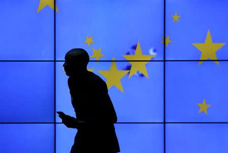 A visitor is silhouetted against an electronic board in the atrium of the European Council (EC) building in Brussels, Belgium, February 2, 2016. REUTERS/Francois Lenoir