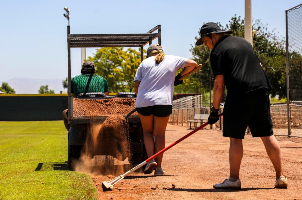 Members of the grounds crew work to add dirt along the edge of the first base grass line at Palm Springs Stadium in Palm Springs, Calif., Wednesday, May 25, 2022.