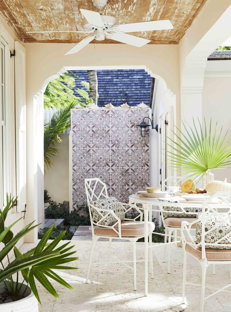 the outdoor shower’s portuguese cement tilework reads like antique wallpaper against the white outdoor dining furnture