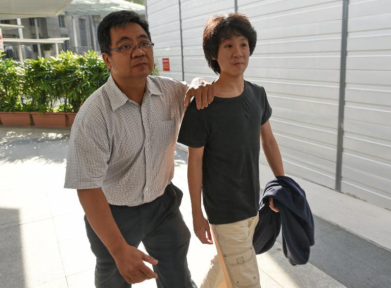 Amos Yee (R), 16, arrives with his father at the State courts in Singapore, on March 31, 2015