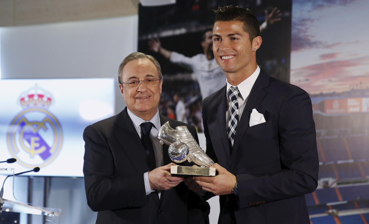 Real Madrid's Cristiano Ronaldo (R) receives a trophy from club's president Florentino Perez  during a ceremony at Santiago Bernabeu stadium in Madrid, Spain October 2, 2015. Real Madrid paid homage to Cristiano Ronaldo as their leading scorer on Friday even though the official statistics show he is yet to overhaul former Spain striker Raul. The plate on the trophy reads in Spanish 