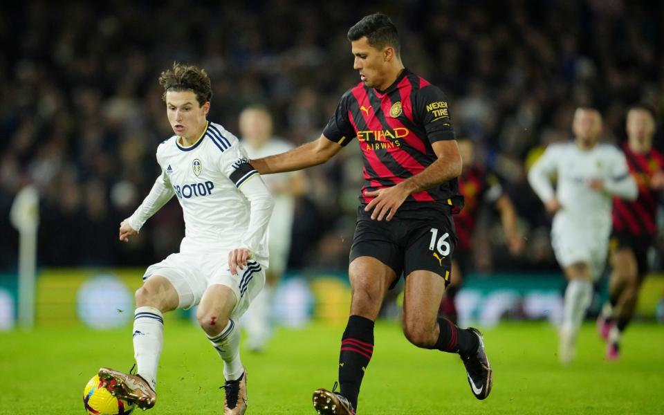 Leeds United's Brenden Aaronson, left, challenges for the ball with Manchester City's Rodrigo - AP