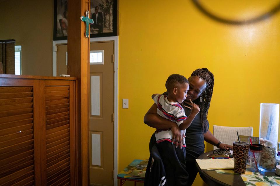 Tenai Leali, 47, of Detroit, holds her son Josiah Sims, 2, while she works from home in Detroit on Sept. 27, 2022. Leali inherited her grandparent's home but the property isn't in her name, and she worries about not being able to pass the home down to her children.