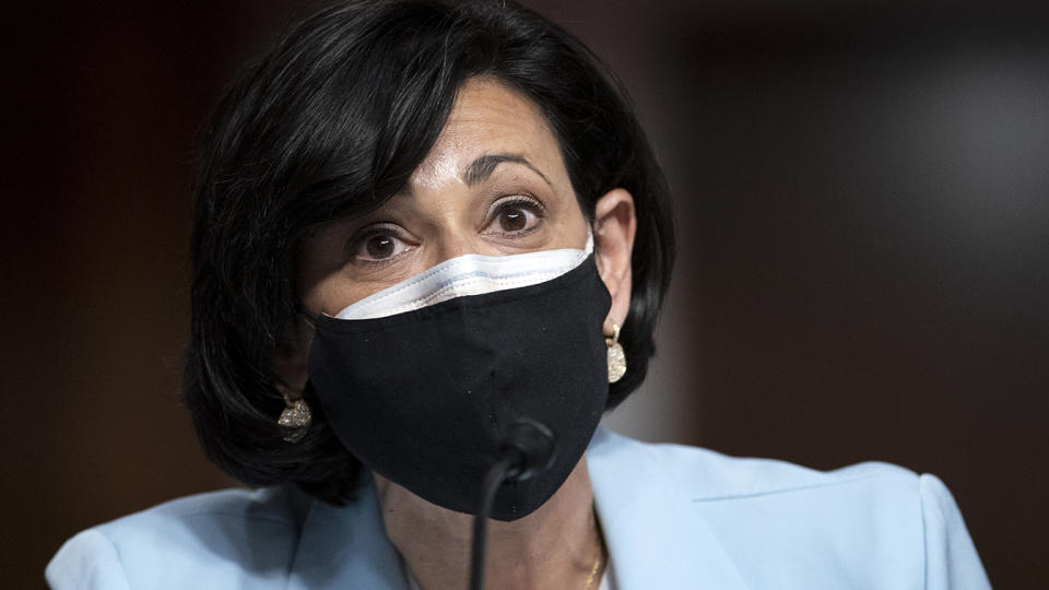 CDC Director Rochelle Walensky, wearing protective face masks, sits before a microphone at a Senate hearing.