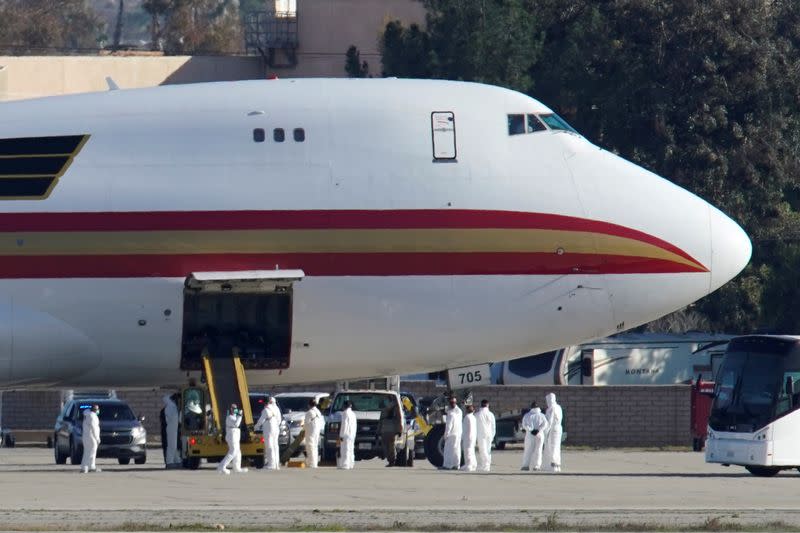 Personal con ropa protectora se acerca a un avión en la Base Aérea March en el Condado de Riverside, California, que trae a los evacuados estadounidenses de Wuhan en China.