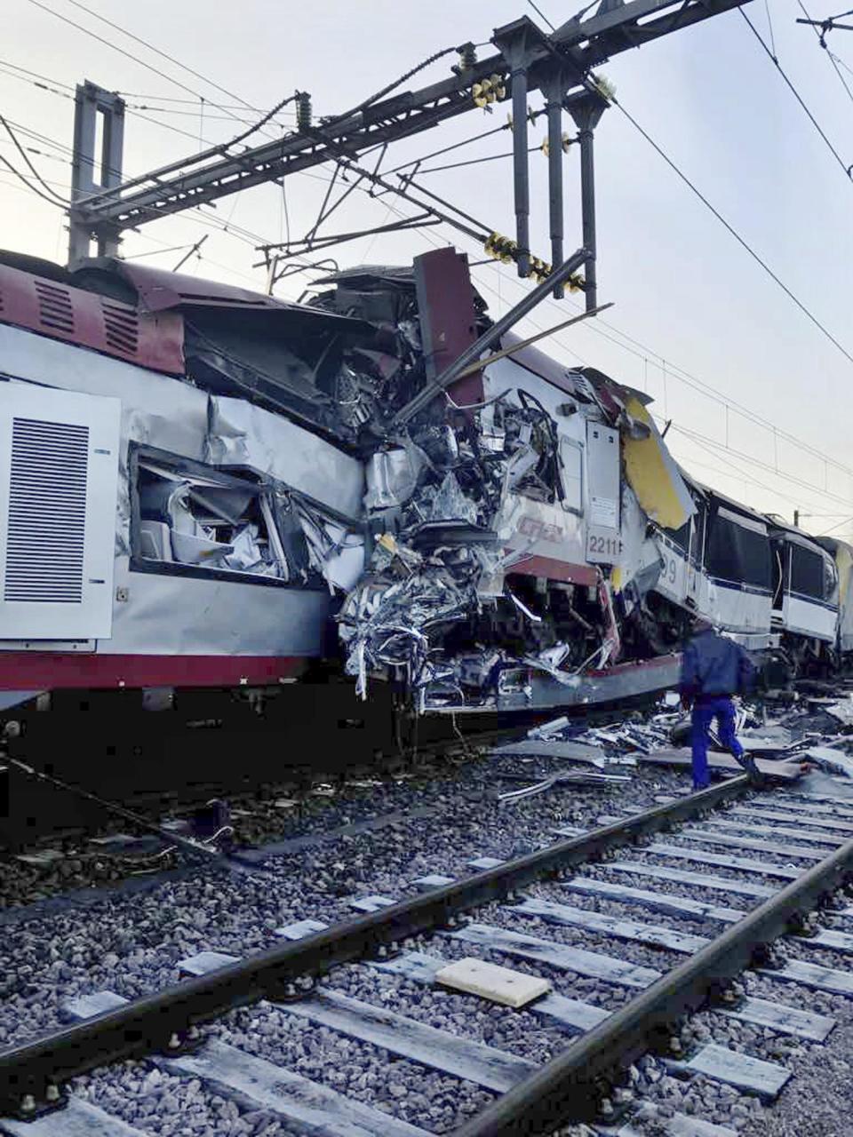 In this image provided by the Luxembourg Police Grand Ducale, a man walks near the wreckage of a passenger train and a freight train after they collided in Bettemberg, Luxembourg on Tuesday, Feb. 14, 2017. The collision left one person dead and at least four injured. (Luxembourg Police Grand Ducale via AP)