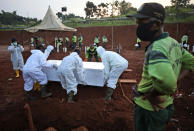 FILE - In this Sept. 24, 2020, file photo, workers lower a coffin containing the body of a suspected COVID-19 victim into a grave during a burial at the special section of Pondok Ranggon cemetery which was opened to accommodate the surge in deaths during coronavirus outbreak, in Jakarta, Indonesia. The worldwide death toll from the coronavirus eclipsed 1 million, nine months into a crisis that has devastated the global economy, tested world leaders' resolve, pitted science against politics and forced multitudes to change the way they live, learn and work. (AP Photo/Dita Alangkara, File)