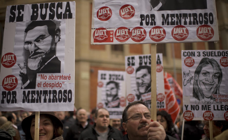 People holds placard with cartoons of the Spanish Primer Minister Mariano Rajoy and Maria Dolores de Cospedal reading: '' Wanted for Liar '' as they protest against the economic policy of the Conservative Spanish Government during a rally in Pamplona, northern Spain, Sunday, Feb. 19, 2012. The new conservative Popular Party government pledges new labor reforms to try to halt further job destruction as Spain already has the highest unemployment rate in the 17-nation eurozone with more than five millions unemployed and more than eleven million people are poor and at risk of social exclusion, by the strong economic crisis. (AP Photo/Alvaro Barrientos)