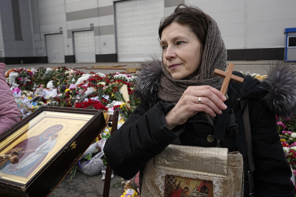 An Orthodox believer attends a service at a makeshift memorial in front of the Crocus City Hall on the western outskirts of Moscow, Russia, Tuesday, March 26, 2024. Russian state news agency Tass says 22 victims of the concert hall attack that killed more than 130 people remain in serious condition in the hospital. (AP Photo/Alexander Zemlianichenko)