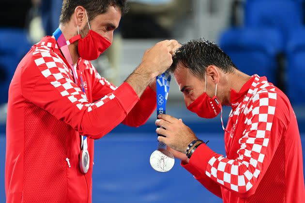 Silver medallist Marin Cilic of Croatia, left, gives Croatia's Ivan Dodig his silver medal on the podium during the men's doubles tennis ceremony at the Ariake Tennis Park in Tokyo on July 30. (Photo: VINCENZO PINTO via Getty Images)