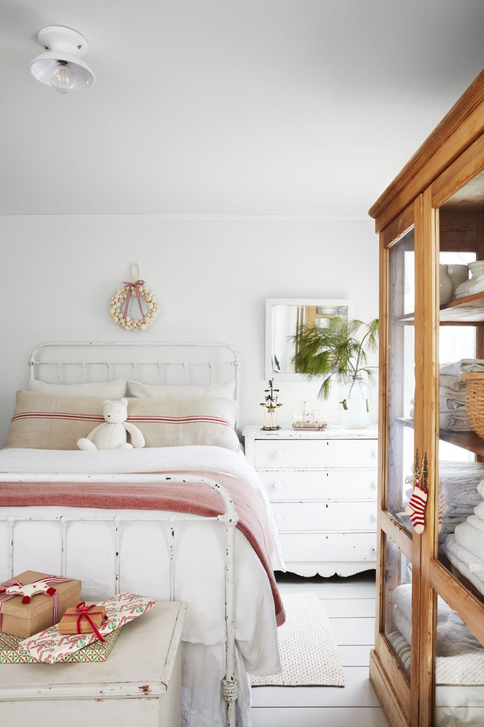 white cottage bedroom with white iron bed, light layer of christmas decorations